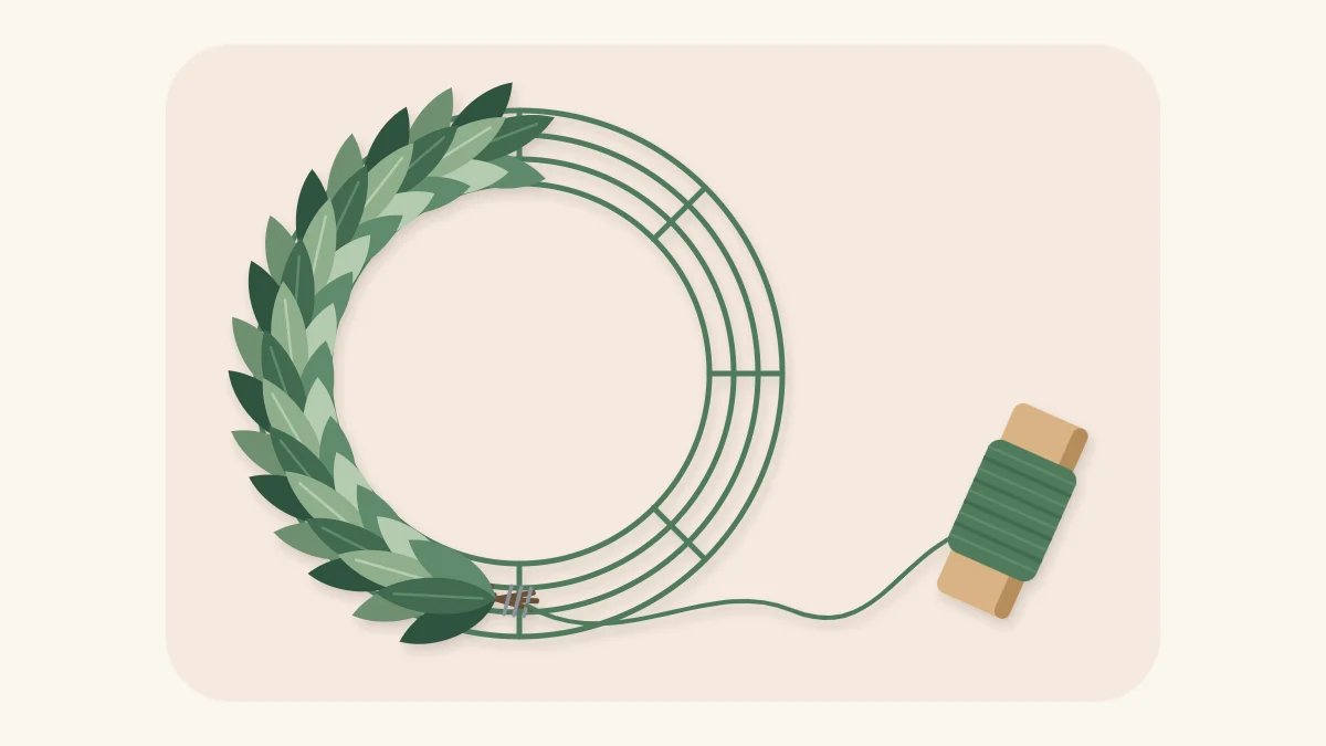 Half-finished greenery wreath on a wire frame with paddle wire still attached
