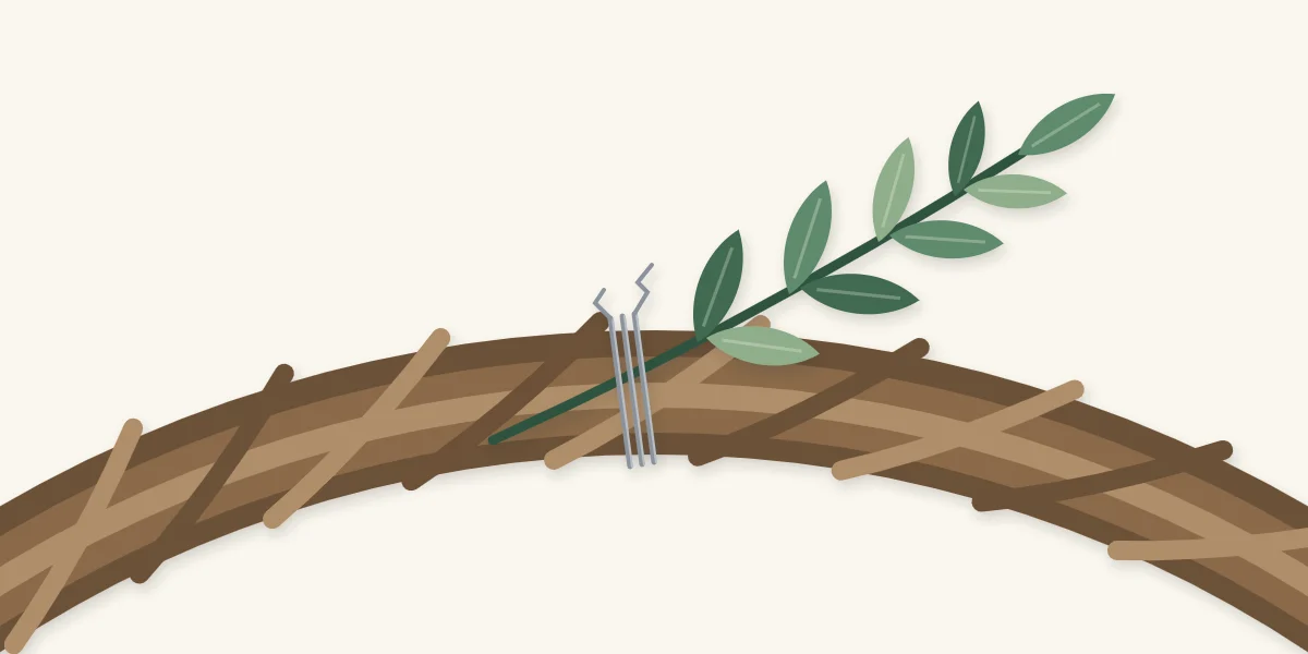 Leafy stem tucked between grapevine strands and secured with thin wire