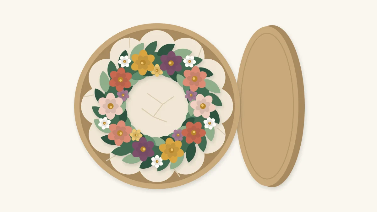 Faux flower wreath lying flat on tissue paper in an open round storage box